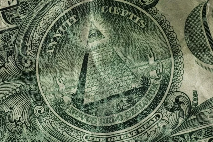 Close-up of a United States one-dollar bill showing the Great Seal with the Eye of Providence above an unfinished pyramid.